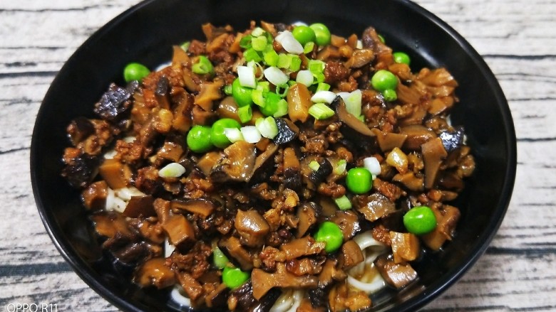 香菇杂酱面,煮好的面捞出放在放了青菜的碗里,舀上一大勺香菇肉酱,撒上青豆和葱花,香菇杂酱面就做好啦!香喷喷的