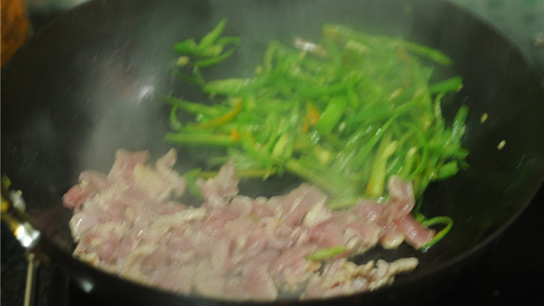 青椒肉丝,炒至八成熟的青椒扒拉到锅边,锅里再加入少许油,将肉丝倒进去,炒至变色