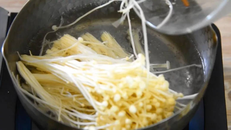 金针菇控们在哪里?赶快来围观,烧开一锅水,下金针菇煮沸,捞出备用。