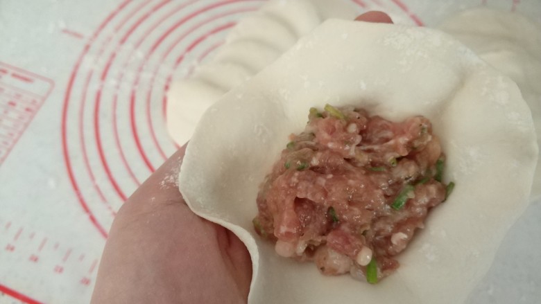 鲜肉生煎发面饼,取一小份面团擀成四周薄中间厚的面片、包入肉馅、捏紧收口。