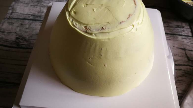 福袋、钱袋蛋糕,取2/3奶油加入少量黄色色素拌匀,把蛋糕胚抹好面,用软刮板比较好用。顶部不用特别平,一会就盖住了。