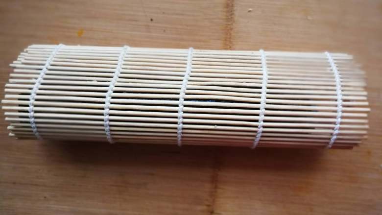 花朵寿司【蓝色系】, 对折,压实卷帘两端,中间不要用力压。(前端的米饭不要长过另一端的黄瓜,不然做好的花瓣黄瓜就不在顶端了)