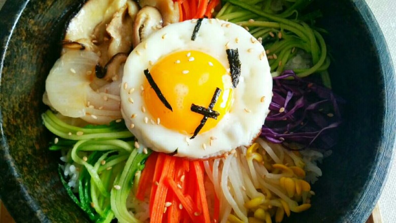 石锅拌饭,米饭铺底,摆上蔬菜,辣酱,鸡蛋,撒上白芝麻,海苔碎