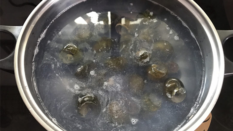 剁椒田螺酿肉,锅中倒入适量清水煮开,把田螺放入锅中。