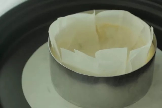 流心芝士挞,将一张8寸圆形烘焙纸边缘剪碎成风扇状,方便折叠包裹住饼干挞不变形。