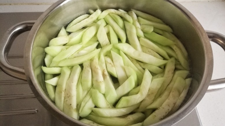 家常炒茄丝,锅中水烧开,放入切好的茄丝焯水。