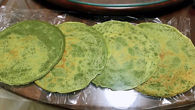 抹茶草莓毛巾卷,先铺一层保鲜膜,4张抹茶皮依次叠放好
