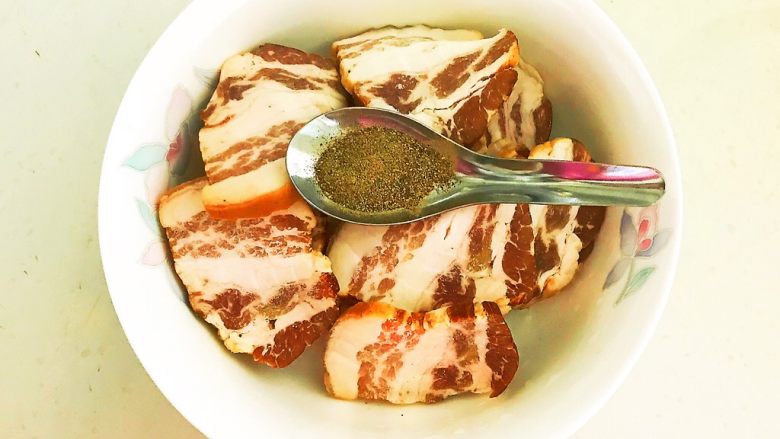苦菊卷黑椒腊肉,把切好的腊肉放入碗中,加入1勺黑胡椒粉