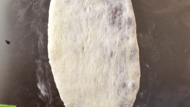 可可牛奶双色花纹吐司,松弛好的面团压扁,擀成牛舌状。