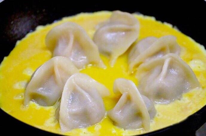 煎饺抱蛋,锅里还有少许水的时候倒入打好的蛋液,小火。盖上锅盖,让鸡蛋凝固