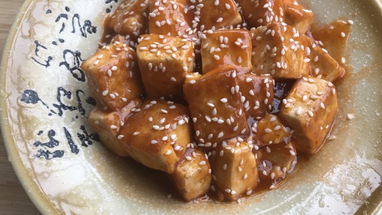 做道小朋友也爱吃的酸甜豆腐,豆腐倒入盘中,洒上<a style='color:red;display:inline-block;' href='/shicai/ 678'>白芝麻</a>装饰。