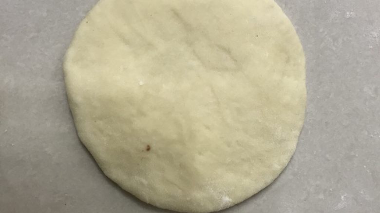 铁棍山药芝士包,取一个松弛好的面团用手掌拍扁,用擀面杖擀成圆面片