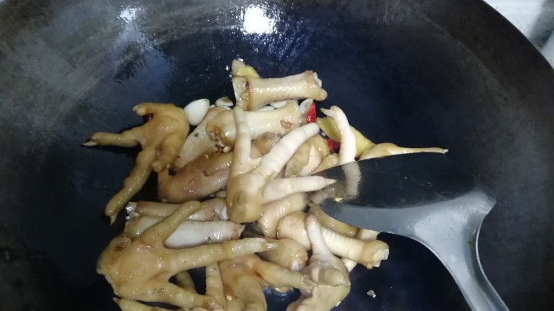 红烧鸡爪,加入姜蒜辣椒,酱油(酱油的量为使鸡爪变色为好)和料酒,翻炒,