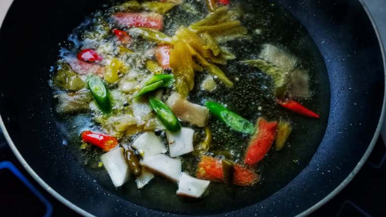 香煎鲫鱼,热锅下植物油,油7成熟时下泡椒、酸菜、部分青椒(前取一半青椒味增香、后取一半青椒貌增色)、香菇柄第炒香;