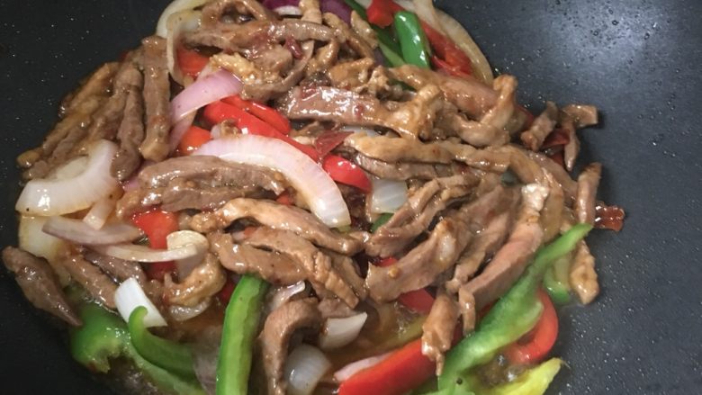青椒炒肉丝,用锅铲将肉丝铲在青椒红椒洋葱上面盖住焖20秒,最大限度保证菜炒熟、入味。