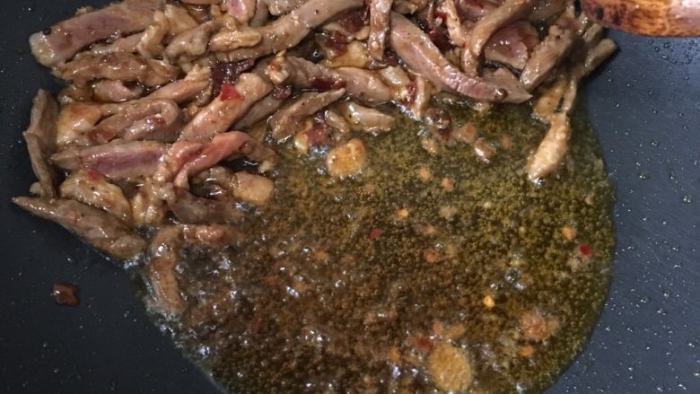 青椒炒肉丝,肉丝炒断生后,用锅铲将肉丝铲在一边上,最大限度溢出油在锅底。