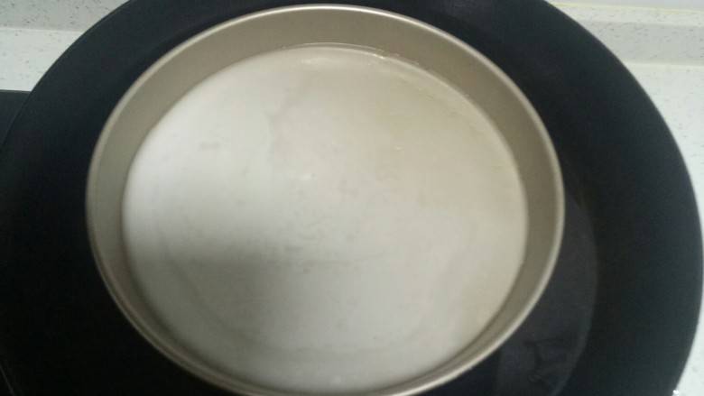 自制凉皮,锅中放入适量水,水开后转中火,披萨盘中盛入1勺搅拌均匀的面汁,放入锅中。