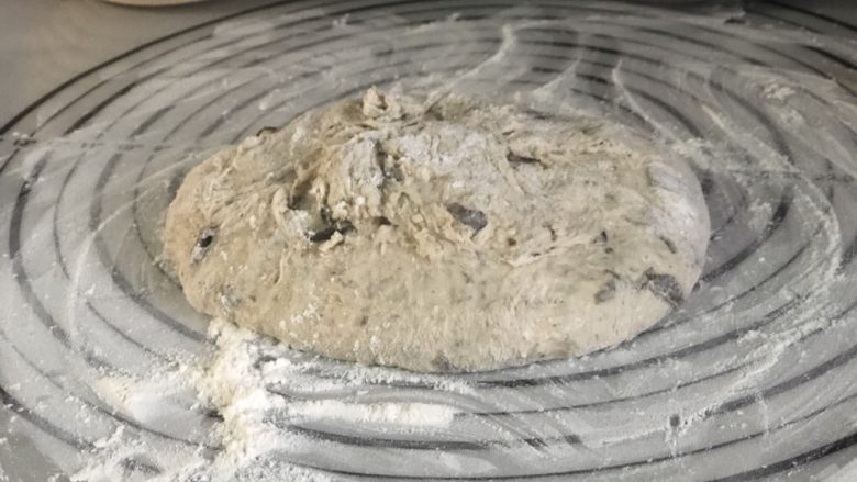 天然酵种橄榄菜欧包,3小时后,取出面团。在垫子上撒一些干粉,滚圆。使面团表面绷紧。