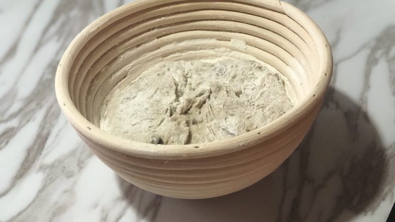 天然酵种橄榄菜欧包,在藤篮中撒一层干粉,面团光滑的一面朝下放入藤篮。盖上保鲜膜,冰箱冷藏发酵过夜。