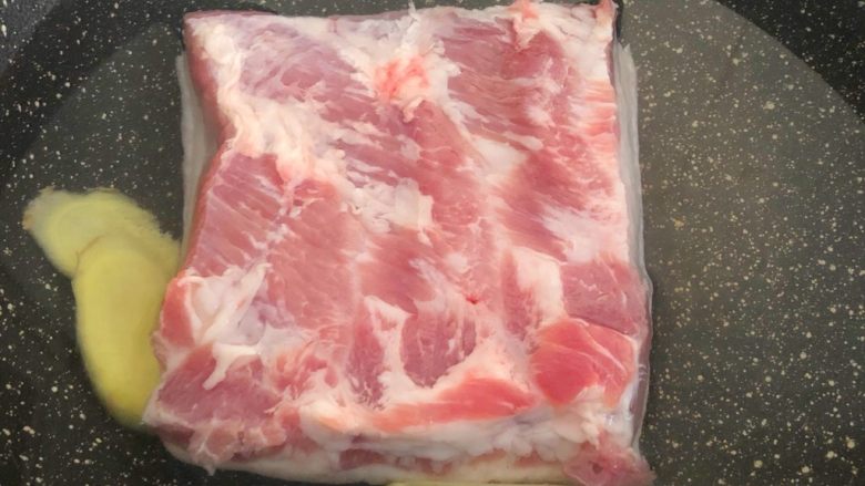 梅菜扣肉,把五花肉和姜片放入锅里,加入冷水,水量以盖过五花肉为准,大火烧开,转中火煮至肉熟透