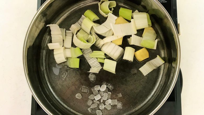 东北特色菜 猪肉炖粉条,炒锅烧热后加入1小勺大豆色拉油,油烧热后加入冰糖,葱段和姜片