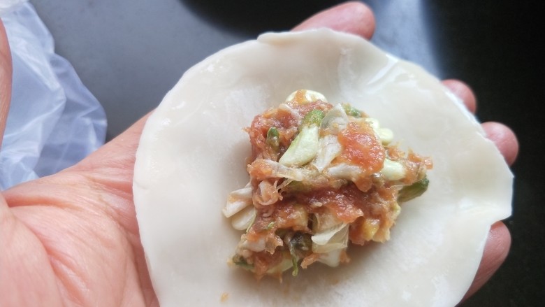 槐花馅饺子,饺子皮的边缘抹上清水,放适量的肉馅。