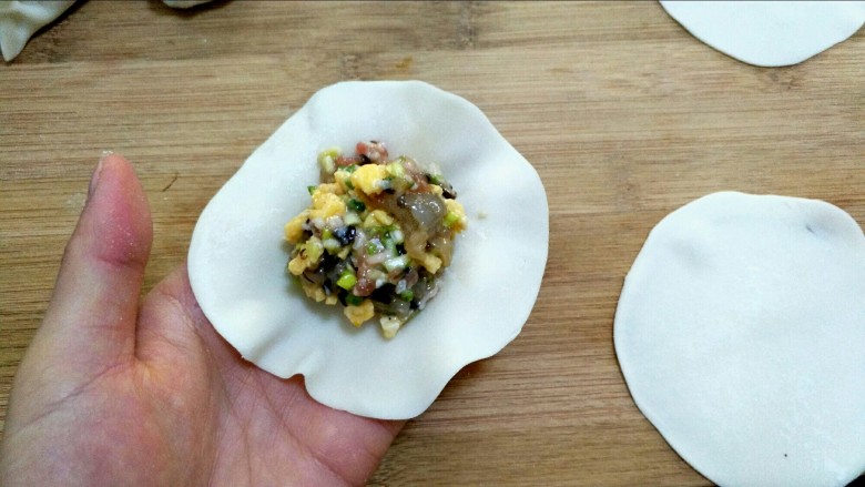 三鲜饺子的多种吃法,饺子皮我买的是现成的,回家再用擀面杖稍微擀薄一些。加入适量馅儿放到饺子皮中间。