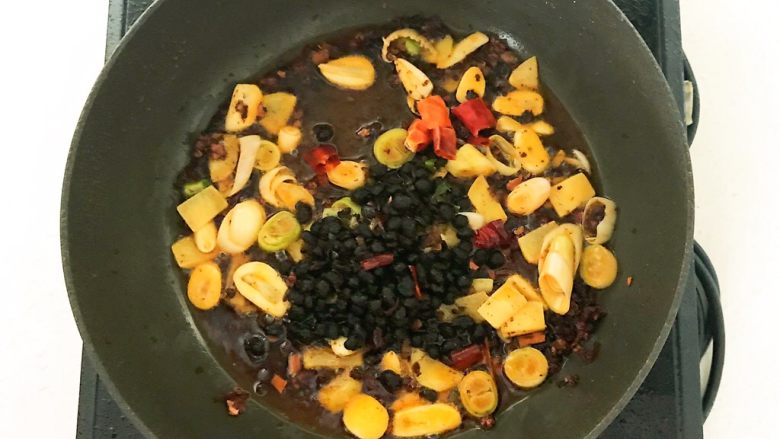 红烧武鲳鱼,加入花椒粒,加入大葱段,蒜片和姜片,翻炒出香味,加入豆豉