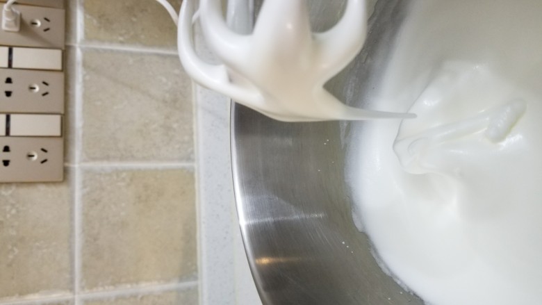 玫瑰奶油蛋糕卷,取出冷冻的蛋白,分三次加入细砂糖打发至提起打蛋头蛋白霜会滴落,并呈90度大弯钩,蛋白霜细腻但有流动性