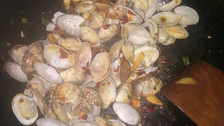 辣炒蛤蜊,配料翻炒几下倒入备用的蛤蜊再次进行翻炒,1分钟后倒入少许<a style='color:red;display:inline-block;' href='/shicai/ 718'>料酒</a>和酱油,(2分钟后用勺子尝一下味道若太咸了再加碗水,若不咸直接可以出锅)