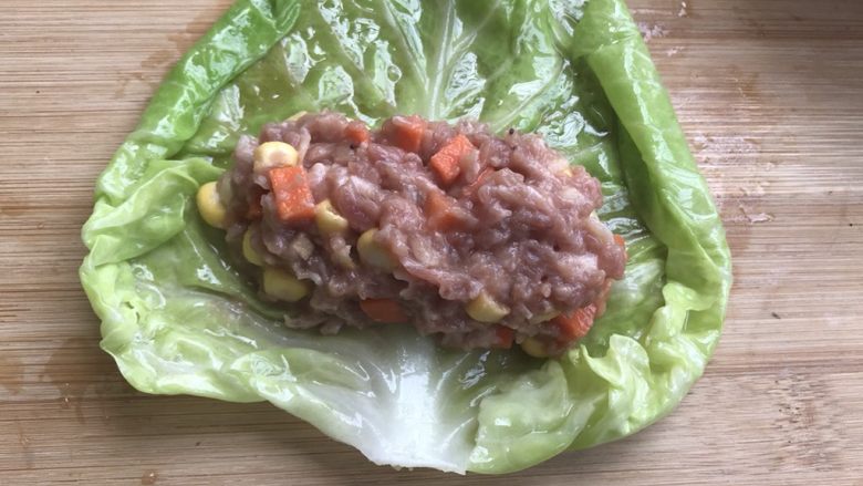 这样荤素搭配极好的,翡翠白玉卷,等菜叶不那么烫手时,平铺,把肉馅均匀大小放在菜叶上,先从下到上卷,再折右边,再折左边,最后一直往前卷,收口朝下。