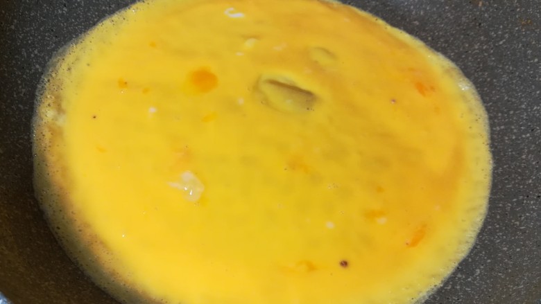 韭苔炒鸡蛋,慢慢晃动锅,摊成一张圆的鸡蛋皮,锅小的可以分两次来摊。