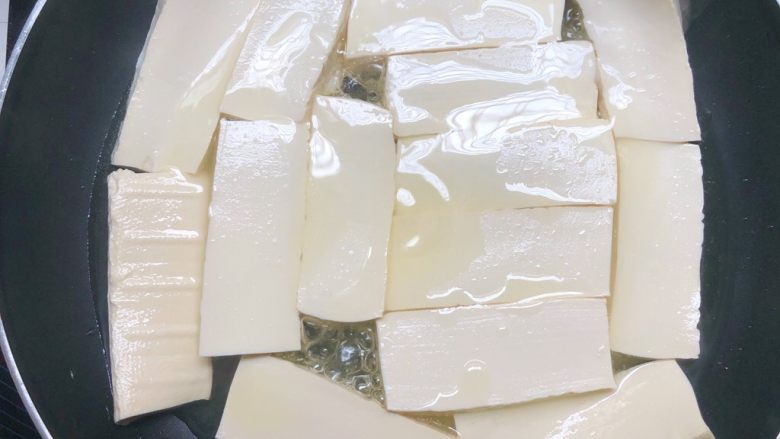孜然豆腐,平底锅放适量油,放入豆腐中火煎制