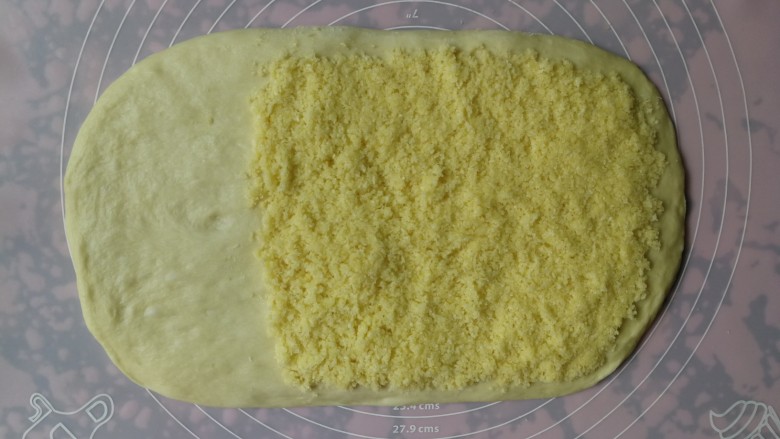 手撕椰蓉面包,一发完成的面团倒在揉面垫上,用手按压排气后擀成长方形,然后将椰蓉馅料平铺在面团的2/3处,留1/3不铺馅料