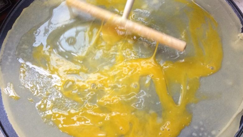 煎饼果子,用刮板将鸡蛋打散,刮开