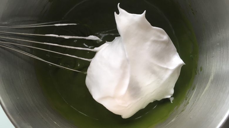 香蕉抹茶慕斯蛋糕,取三分之一打发的蛋白霜,加入到抹茶面糊中,先用蛋抽翻拌均匀,烤箱预热160度