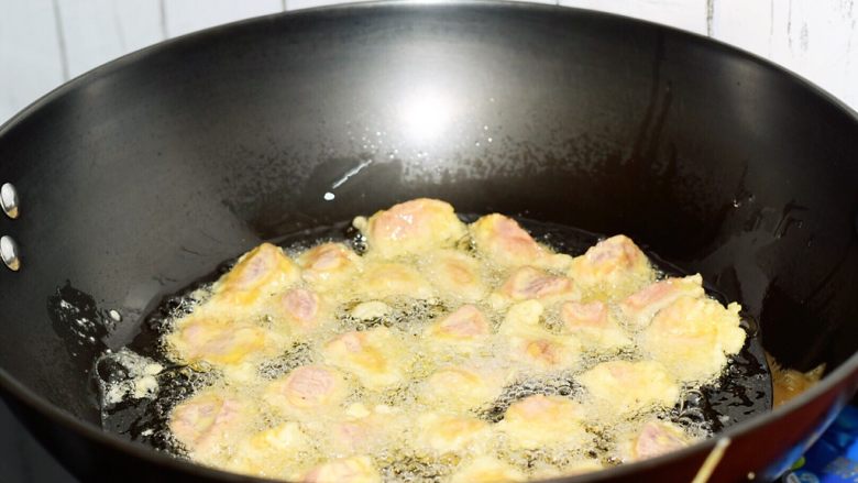 菠萝咕噜肉,锅中倒入适量的食用油烧至6-7成热,然后把肉块一个一个的下入油锅中,这样才不会让肉块粘在一起,小火炸至变色定型