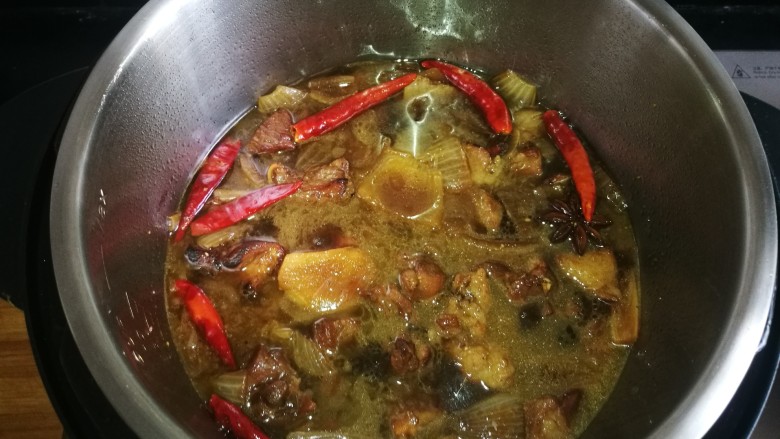 正宗新疆囊包肉,待羊肉变色有些焦黄时加入开水,移至高压锅中,继续加热。