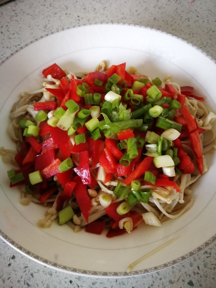 美味凉拌金针菇,金针菇装盘，上面洒红椒丁，葱花，然后加2勺左右的蒸鱼豆豉。