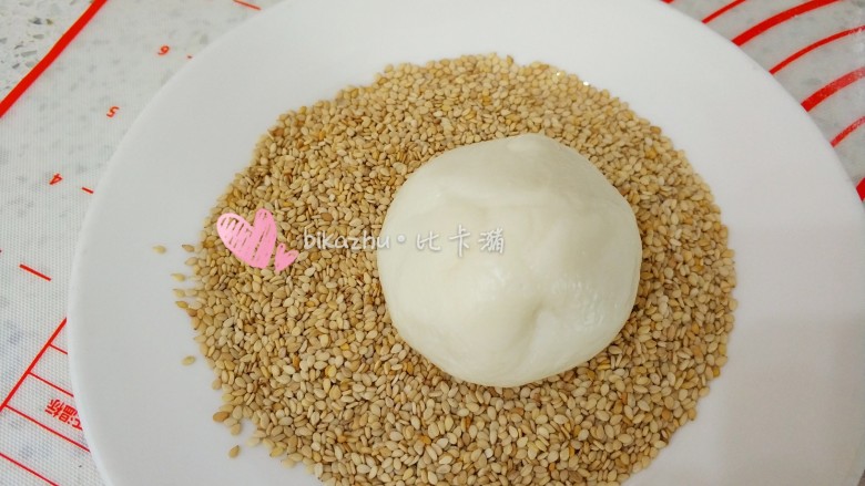 生煎红豆夹心糯米糍,包进馅料收紧收口,放在芝麻上