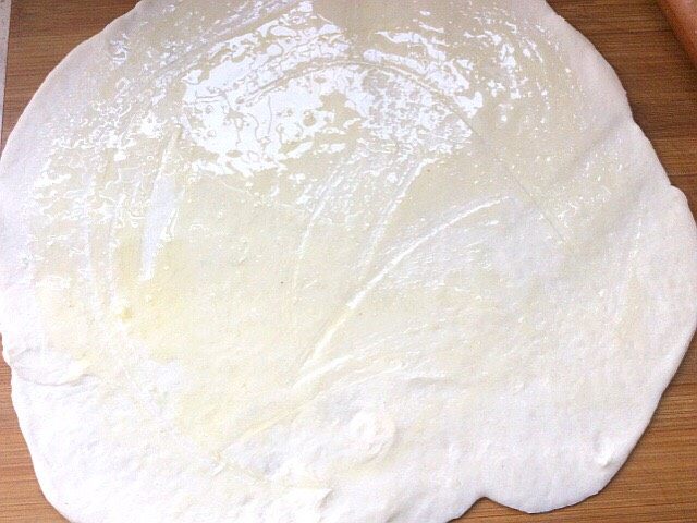 烫面葱花饼,擀成圆面皮,刷上油,在卷起