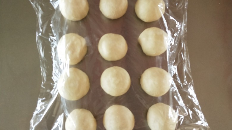 香葱芝士小餐包,取出排气,分成12份,滚圆,盖保鲜膜松驰15分钟。