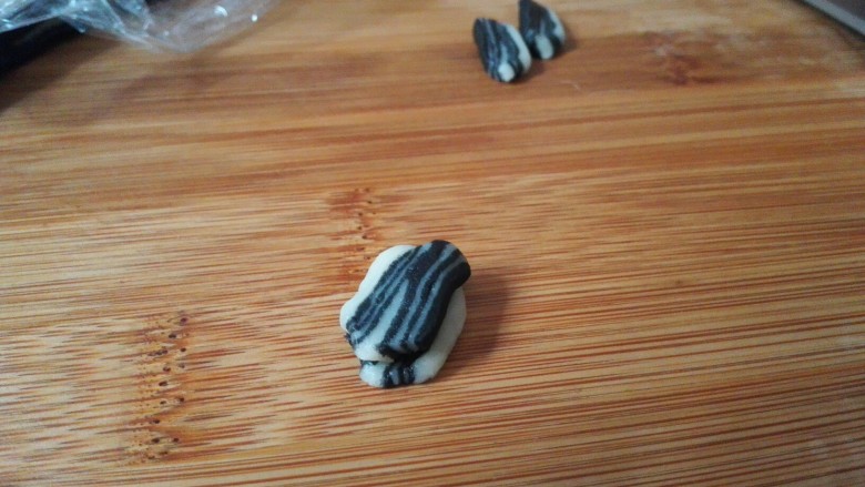 仿真瓜子酥,上面再放上一小片面皮,先把两侧捏紧,再把瓜子尖捏出来,再把瓜子屁股往中间捏紧(如果感觉干,可以在面皮上刷一点点水再捏)。