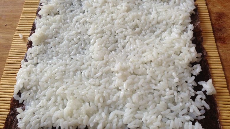 清甜玉米寿司,把米饭平铺在上面压实,注意尾部留出一点不要铺