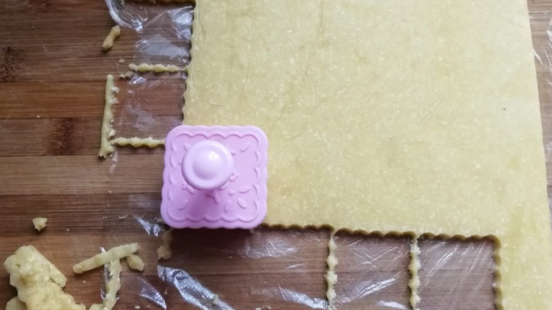 椰蓉芝士夹心饼干,把冻硬的面皮取出来,撕开保鲜膜,再用饼干模具刻下饼干胚