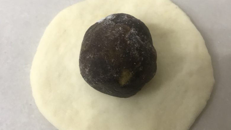 蛋黄豆沙小餐包,取一松弛好的面团用手掌拍扁成圆形面皮边上稍簿,放上蛋黄豆沙馅。