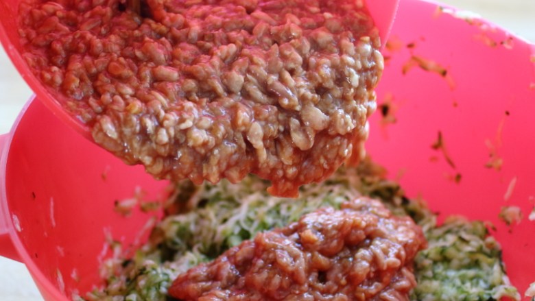 西葫芦鸡肉煎饺,将拌匀的肉泥馅倒入装有西葫芦的调理碗里。