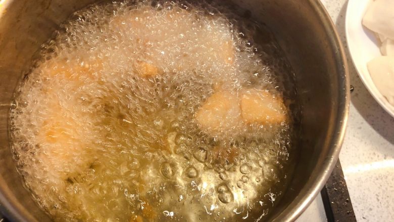 普宁炸豆腐,炸至表面微黄时翻动豆腐,继续炸至两面金黄。