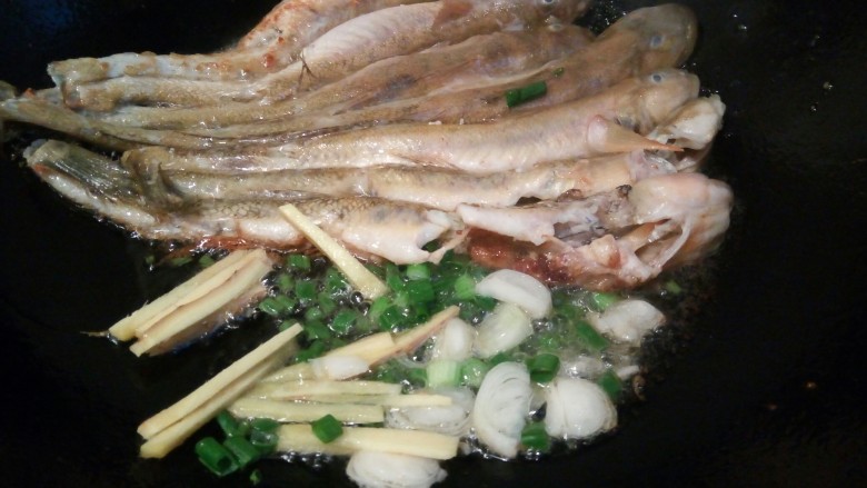 红烧豆豉泥鱼,泥鱼煎好、用铲子轻轻推一边,下生姜,葱花