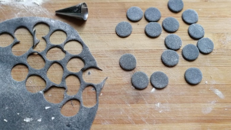 熊猫豆沙馒头,先把黑色面团擀成薄面片,用小号裱花嘴,刻出8对小圆片